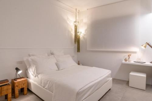 a white bedroom with a white bed and a table at Nest House & Relax in Civitanova Marche