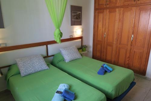 two beds in a room with green sheets at Golondrina 28 - Bungalow fronte Oceano a Matagorda - Piscina - Aria condizionata in Tías