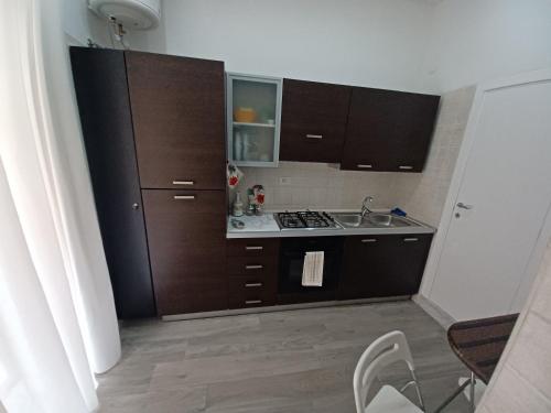 uma pequena cozinha com armários castanhos e um lavatório em Residenza Napoletana em Nápoles