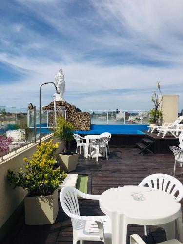 a balcony with white tables and chairs and a statue at Gran Texier Hotel Casino in Concepción del Uruguay