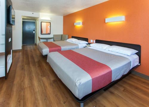 two beds in a hotel room with orange walls at Motel 6-Los Angeles, CA - Los Angeles - LAX in Inglewood