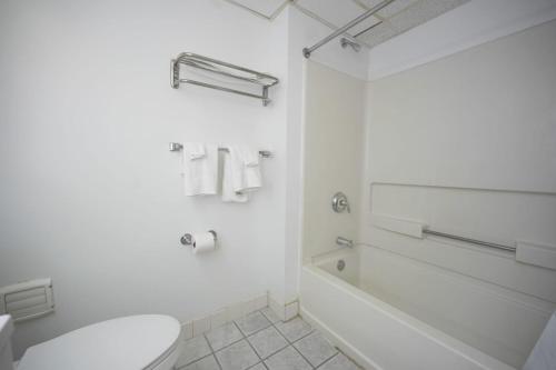 a white bathroom with a toilet and a bath tub at Greenwoods inn & Suites in Berlin