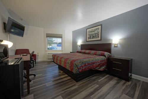 a bedroom with a bed and a desk and a television at Greenwoods Inn & Suites in Berlin