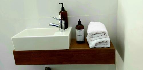 a bathroom sink and towels on a wooden shelf at Andrea Houses in Chacras de Coria