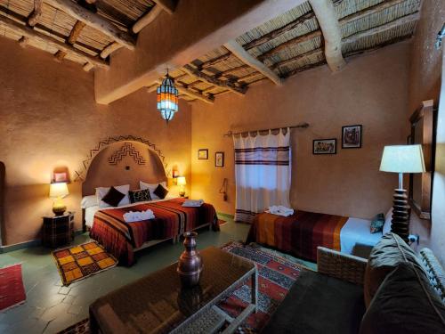 una camera d'albergo con due letti e un divano di Riad Paradise of Silence a Aït Ben Haddou