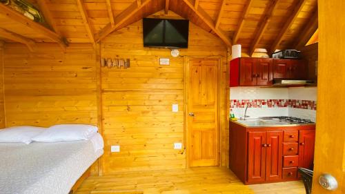 a kitchen with a bed and a television in a room at Villa Angela Glamping & Tiny Houses in Paipa