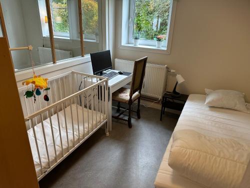 a bedroom with a crib and a desk with a laptop at Lärkan21 Tvisegatan 24C in Borlänge