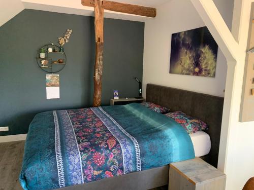 een slaapkamer met een bed met een blauw dekbed bij Gastenverblijf 't Oelengoor in Sinderen