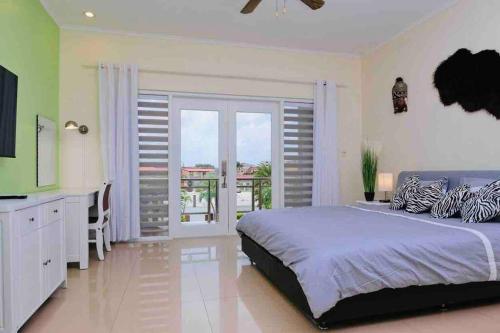 a bedroom with a large bed and a balcony at Eagle Beach Aruba Breeze Condominium Lime in Palm-Eagle Beach