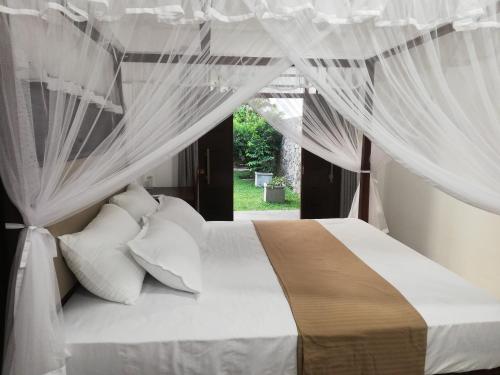 a bedroom with a bed with white drapes at Ceylonray Travels and Holidays in Hikkaduwa