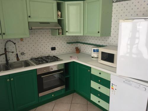eine grüne Küche mit grünen Schränken und einem Waschbecken in der Unterkunft casa 102 in Finale Ligure