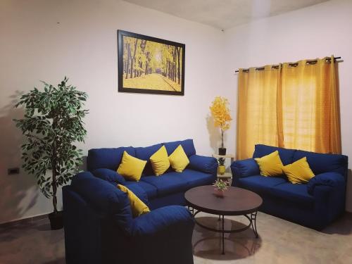 a living room with a blue couch and yellow pillows at casa flores in Bacalar