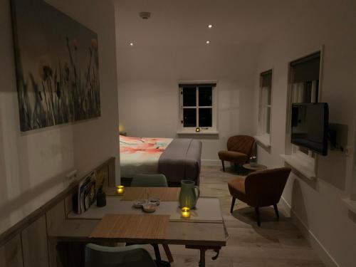 een kamer met een bed en een woonkamer met een tafel bij Gastenverblijf 't Oelengoor in Sinderen