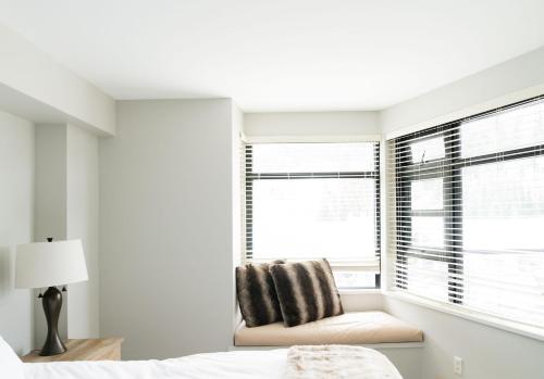 a bedroom with a bed and a chair in front of a window at Gibbons Life Accommodations in Whistler