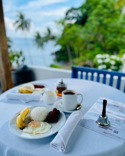 a table with a plate of food and a cup of coffee at Bintana Sa Paraiso in Mambajao