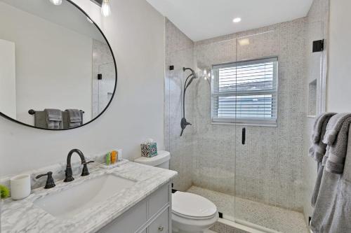 uma casa de banho com um lavatório, um WC e um espelho. em Ariel Beach Cottage em Pompano Beach