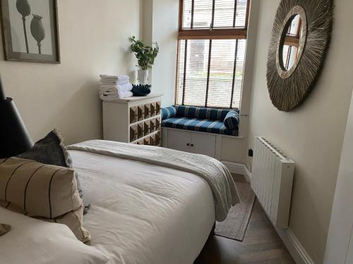 Schlafzimmer mit einem Bett, einem Spiegel und einem Fenster in der Unterkunft Luxurious one-bedroom seaside apartment in Eyemouth