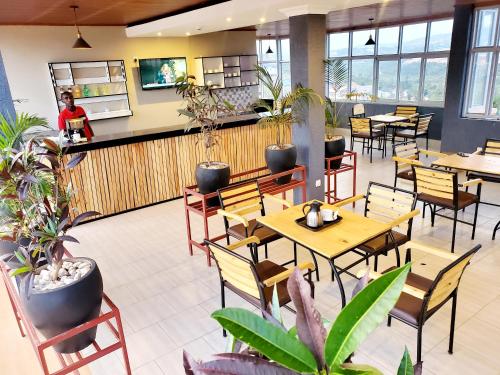 a restaurant with tables and chairs and potted plants at Ebenezer Hotel Apartments in Kigali