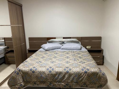 a bedroom with a bed with a blanket and pillows at Sobrado Oktober com Piscina in Santa Cruz do Sul