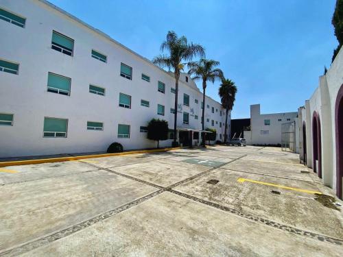 a large white building with palm trees in a parking lot at Hotel Posada Maria Sofia in Cholula