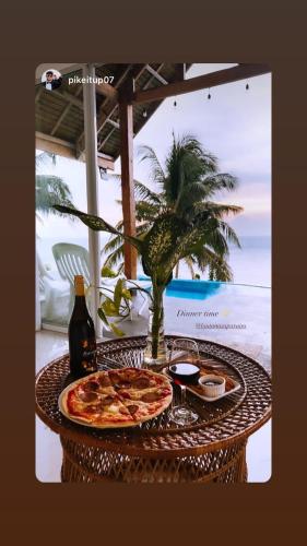 a table with a pizza and a bottle of wine at Bintana Sa Paraiso in Mambajao