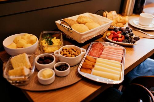 a table topped with different types of cheese and other foods at Vista Vigneti Albergo & Vino - Vale dos Vinhedos in Bento Gonçalves