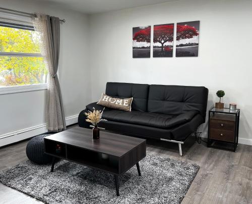 a living room with a black couch and a table at Anchorage midtown apartment- Wyoming 1 in Anchorage