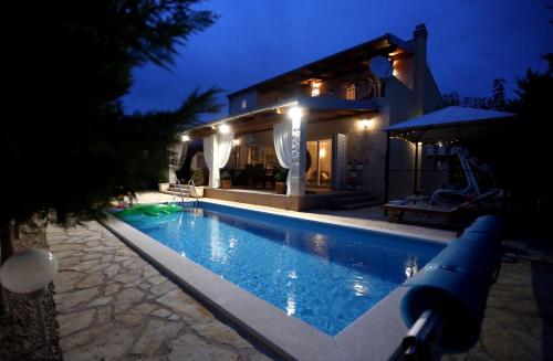 a swimming pool in front of a house at night at Villa Susann in Šibenik