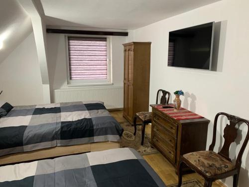 a bedroom with a bed and a dresser and a television at Cheerful 3-Bedroom Getaway in Zărneşti