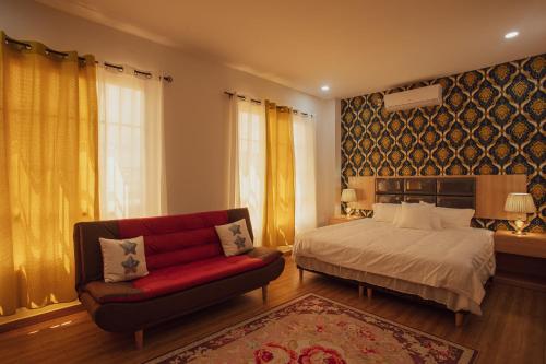 sypialnia z łóżkiem i czerwoną kanapą w obiekcie July AirBnB w mieście Lower Princeʼs Quarter