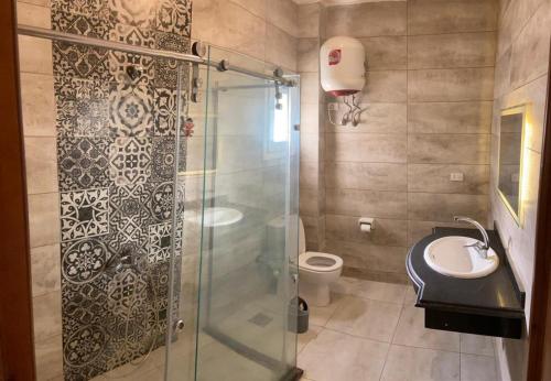 uma casa de banho com um chuveiro, um WC e um lavatório. em Bahga Palace 5 Residential Apartments em Hurghada