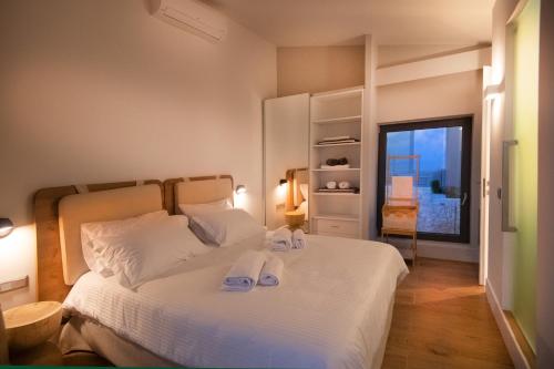 a bedroom with a white bed with towels on it at Dimeli - Sea View Villas in Foinikounta in Finikounta