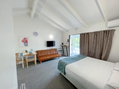 a bedroom with a bed and a couch and a table at Siesta Motel in Auckland