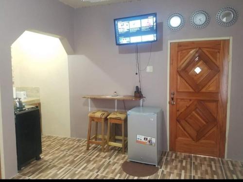 eine Küche mit einem Kühlschrank, einem Tisch und einer Tür in der Unterkunft Mesmerize Guest House in Port Antonio