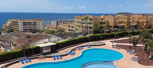 uitzicht op een zwembad met stoelen en de oceaan bij Ocean view apartment in Golf del Sur in San Miguel de Abona