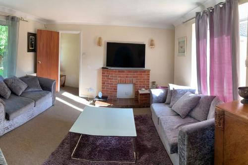 a living room with two couches and a tv at Spacious Furnished Bungalow with Garden n Parking in Bradenham
