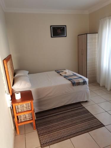 a bedroom with a bed and a table with a night stand at LaMavuso Guesthouse in Krugersdorp