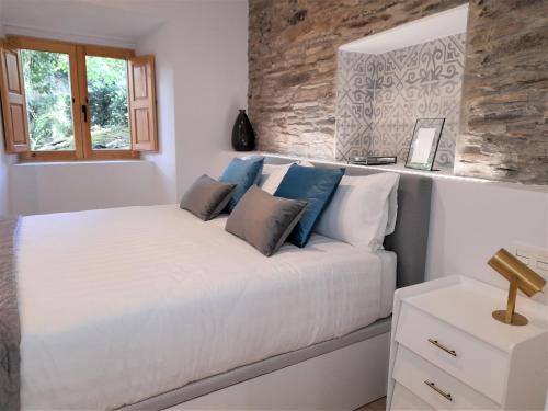 1 dormitorio con 1 cama blanca grande con almohadas azules en Apartamento con encanto en centro histórico Lugo -TineriaLucusHome en Lugo