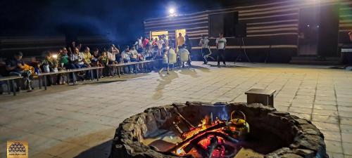 a crowd of people standing in front of a fire at Jabal Rum Camp in Wadi Rum