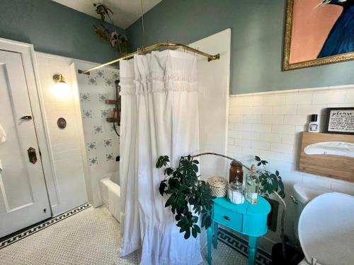 a bathroom with a white shower curtain and a plant at Harbinson House in Sacramento