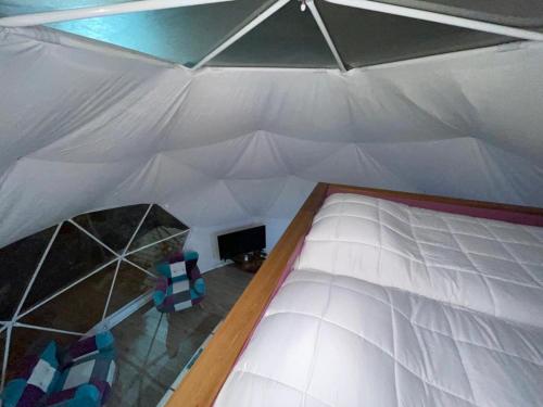 a large white bed in a tent with two chairs at Lodge Los Alerces in Los Muermos