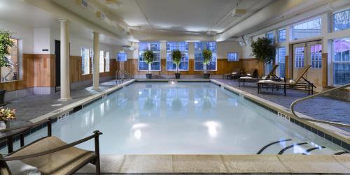 a large swimming pool in a hotel with chairs and tables at Green Mountain Suites Hotel in Burlington