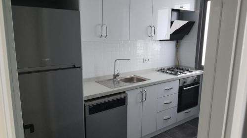 Una cocina blanca con fregadero y refrigerador. en GANİGAR alibeyköy, en Estambul