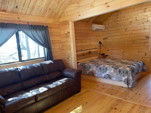 a living room with a couch and a bed in a log cabin at Lakewood Park Campground - Luxury Cabin in Barnesville