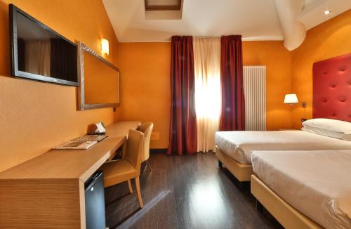 a hotel room with two beds and a desk at Best Western Hotel Piemontese in Bergamo