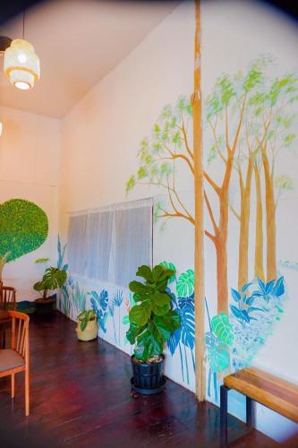 a wall with a mural of trees and plants at Srihome ยายศรีโฮมแอนแคมป์ปิ้ง in Ban Don Tum (1)