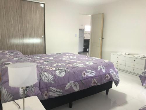 1 dormitorio con 1 cama con manta morada en Berry Dpart en Ushuaia