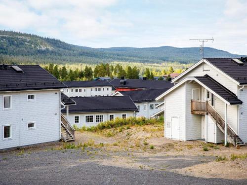 une rangée de bâtiments blancs avec des montagnes en arrière-plan dans l'établissement 8 person holiday home in LOFSDALEN, à Lofsdalen