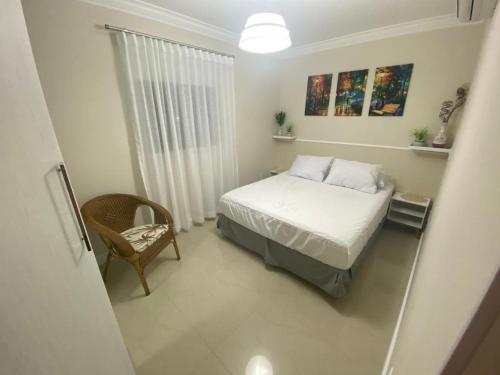 ein kleines Schlafzimmer mit einem Bett und einem Stuhl in der Unterkunft Garden Ville, 200m da Praia de Bombas in Bombinhas