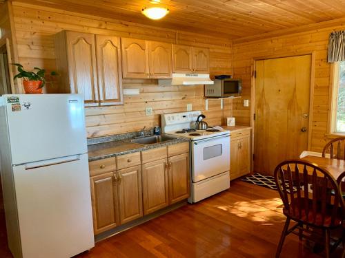 a kitchen with wooden cabinets and a white refrigerator at Clam Gulch Lodge in Clam Gulch